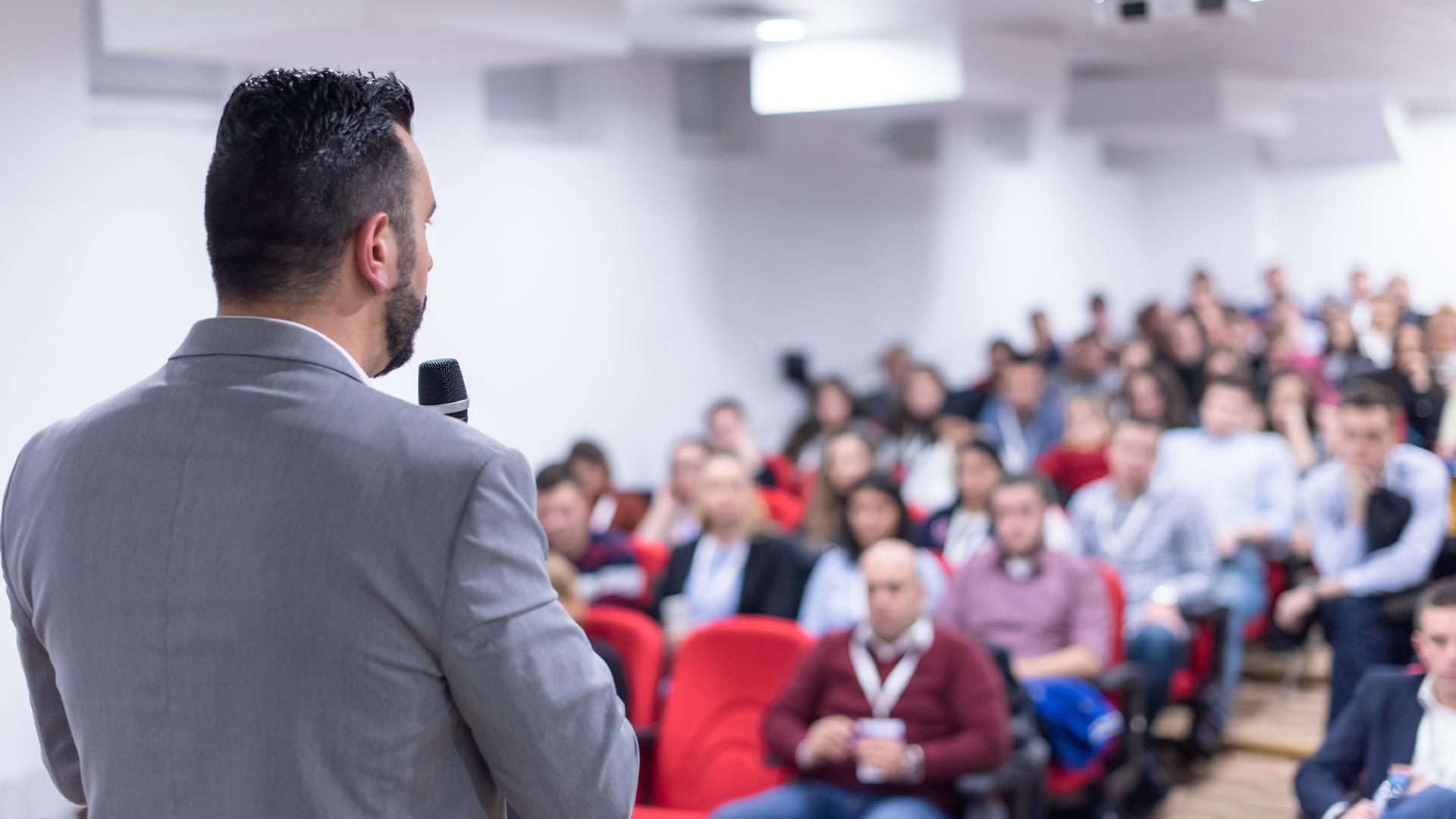 Man in grey suit giving lecture to students